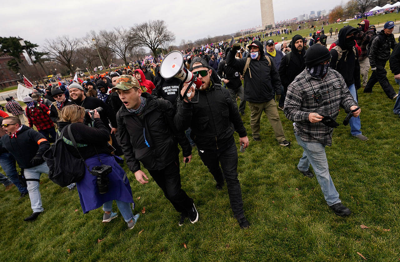Ethan Nordean, with a backward baseball hat and bullhorn, leads members of the far-right group Proud Boys in marching before the riot at the U.S. Capitol on Jan. 6 in Washington, D.C. Nordean, 30, of Auburn, Wash., has described himself as the sergeant-at-arms of the Seattle chapter of the Proud Boys. The Justice Department has charged him in U.S. District Court in Washington, D.C., with obstructing an official proceeding, aiding and abetting others who damaged federal property, and knowingly entering or remaining in a restricted building. He asked a judge Monday, Feb. 8, 2021, to release him from detention pending trial. (Carolyn Kaster / Associated Press file photo)