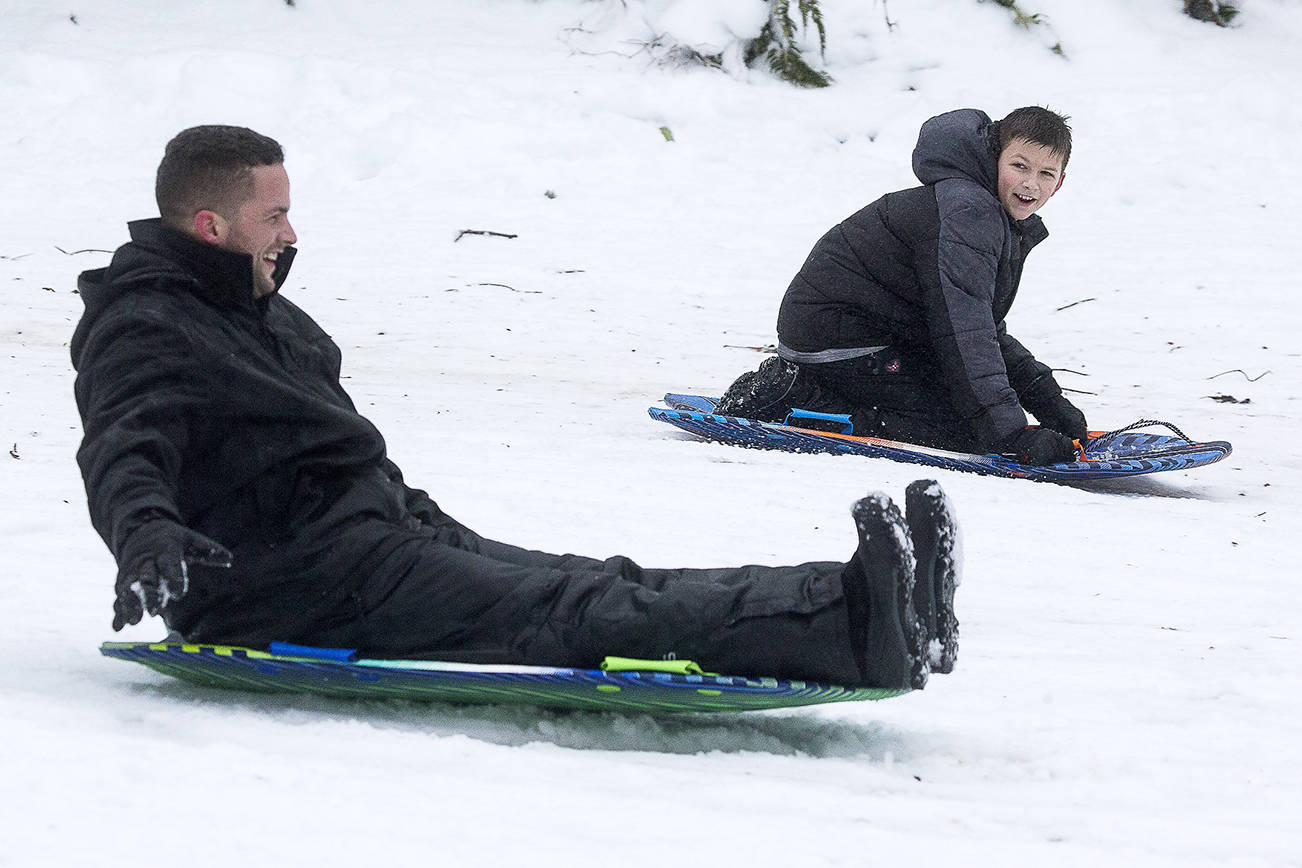 Valentino Toro, right, watches as his father John catches up with him as they go sledding at Forest Park on Monday, Feb. 15, 2021 in Everett, Washington.  (Andy Bronson / The Herald)