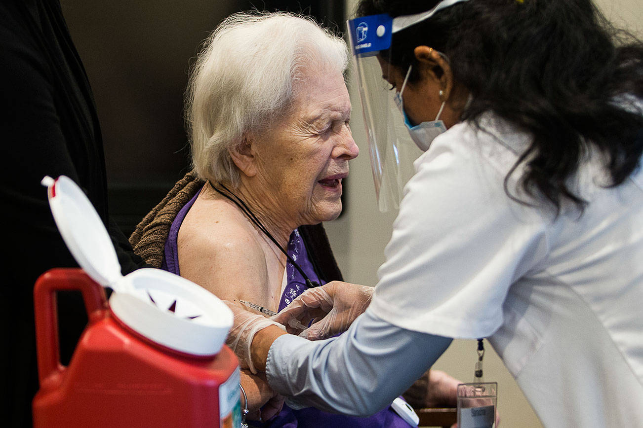 Jackie Hoernor, a resident at South Pointe Assisted Living, winces as she gets her Pfizer COVID-19 vaccination during a Walgreen's Vaccine Clinic at South Pointe on Friday, Feb. 12, 2021 in Everett, Wa. (Olivia Vanni / The Herald)
