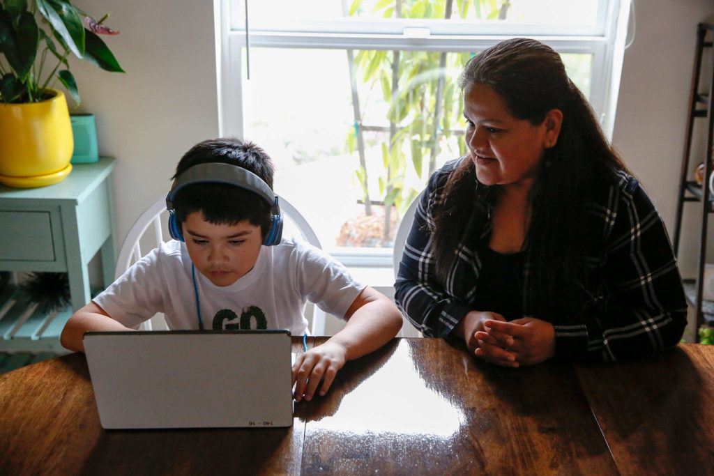 Alma López watches her son Eric Blanquet do school work Friday afternoon in Lake Stevens. (Kevin Clark / The Herald)
