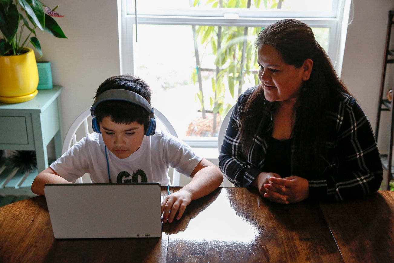 Alma Lopez watches her son Eric Blanquet working through school work Friday afternoon in Lake Stevens on February 19, 2021.  (Kevin Clark / The Herald)