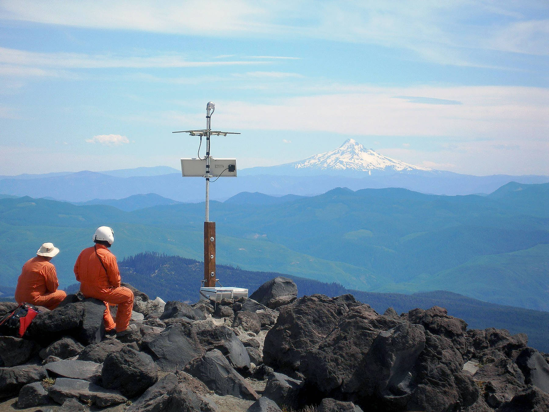 Karl Hagel and Pat McChesney, field engineers with the Pacific Northwest Seismic Network team at the University of Washington, install earthquake monitoring equipment on the slopes of Mount St. Helens, with Mount Hood in the distance. (Marc Biundo / University of Washington)