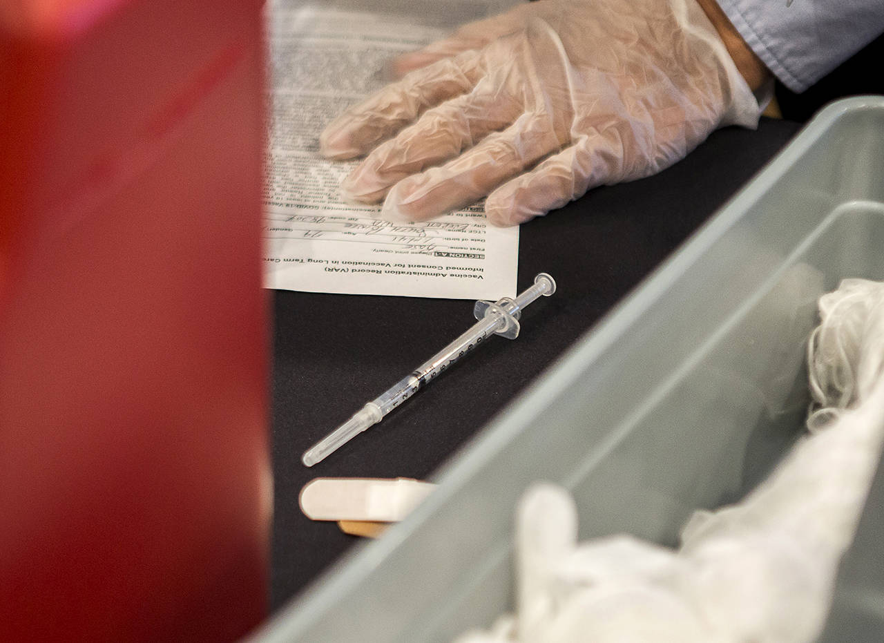 A syringe with the Pfizer COVID-19 vaccine sits on the table during a vaccine clinic at South Pointe Assisted Living on Feb. 12 in Everett. (Olivia Vanni / Herald file)