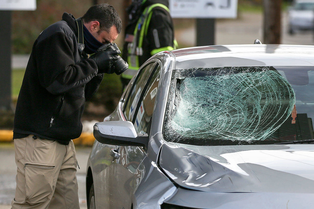 A Washington State Patrol detective photographs the vehicle involved in hit and run double fatality in Bothell Friday on February 19, 2021.  (Kevin Clark / The Herald)