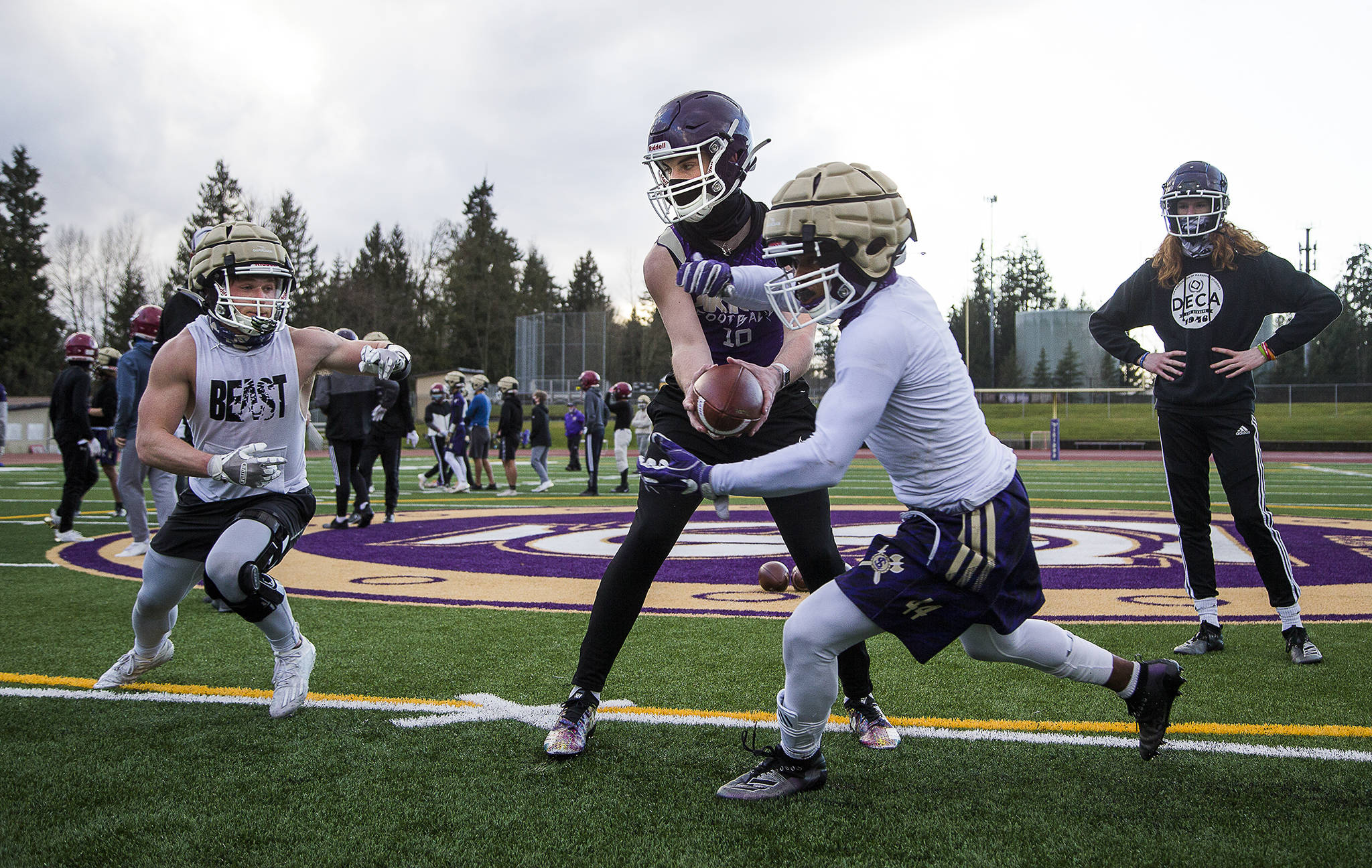 Quarterback Tanner Jellison runs a play with running backs Jay Roughton (left) and Trayce Hanks as the Lake Stevens High School football team conducts its first practice, marking the first day of practice for fall sports in the Wesco division, on Monday in Lake Stevens. (Andy Bronson / The Herald)