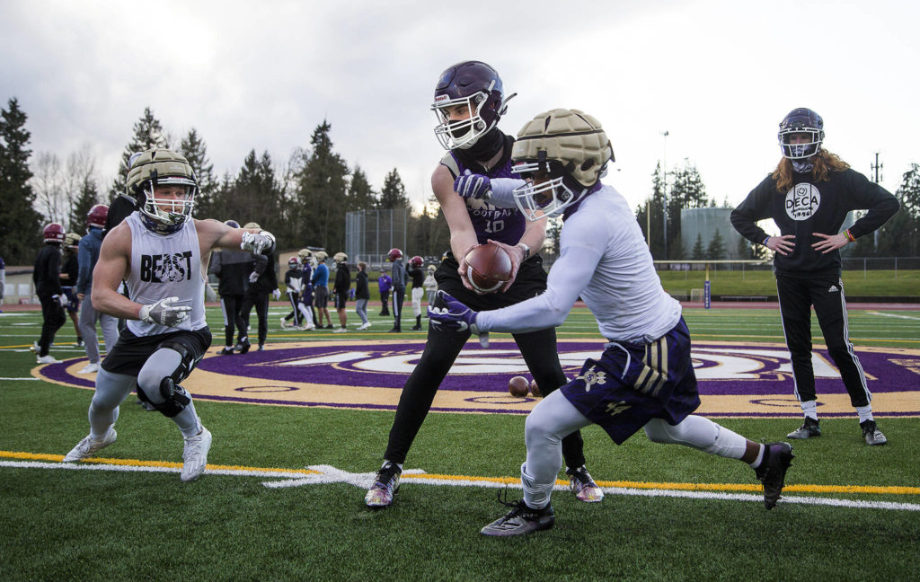 Quarterback Tanner Jellison runs a play with running backs Jay Roughton (left) and Trayce Hanks as the Lake Stevens High School football team conducts its first practice, marking the first day of practice for fall sports in the Wesco division, on Monday in Lake Stevens. (Andy Bronson / The Herald)
