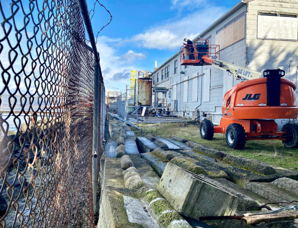 A worker on Tuesday covers windows with boards on the back side of the Mukilteo Research Station that will be torn down and not be rebuilt. (Andrea Brown / The Herald)

