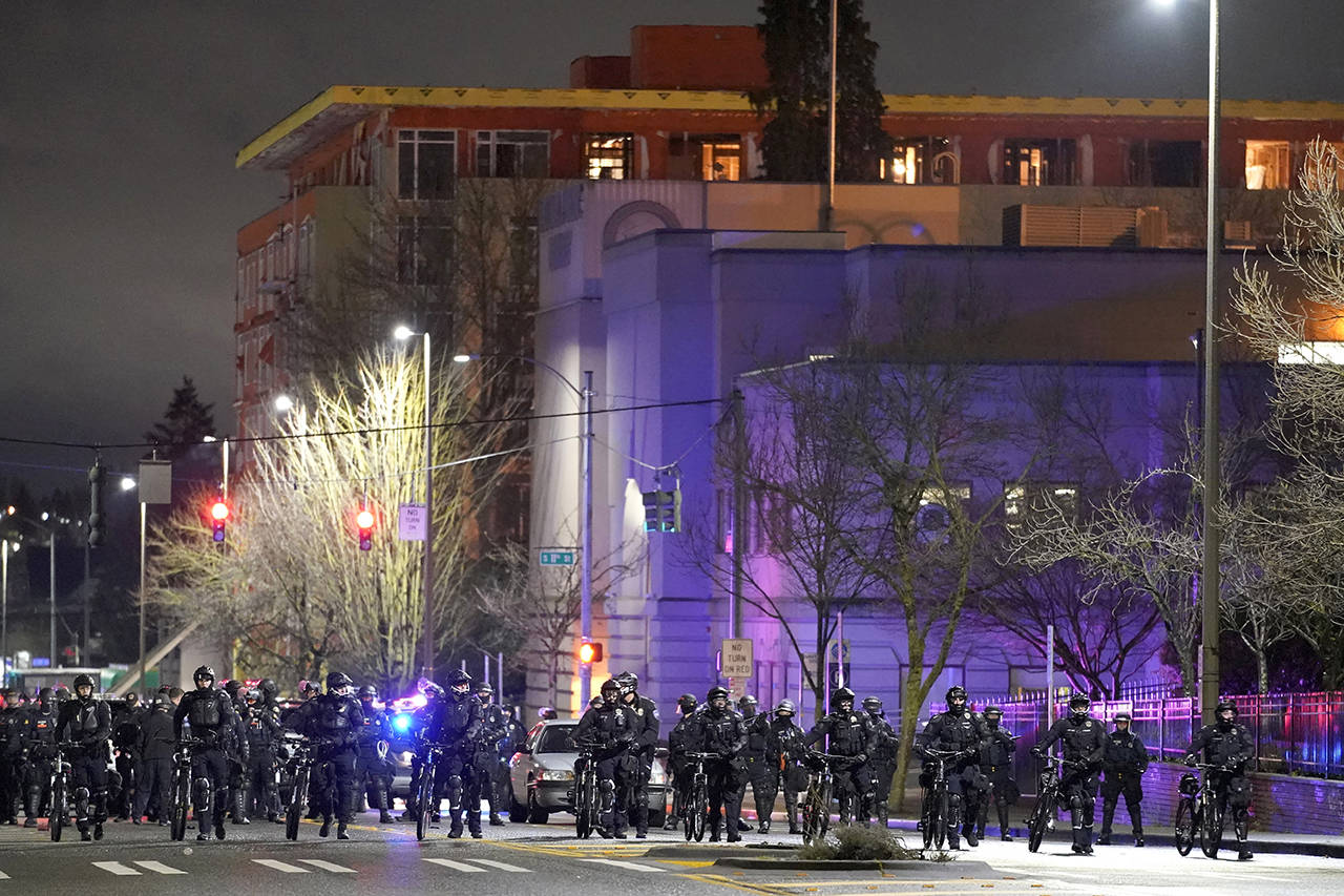 Tacoma Police and other law enforcement officials stand in a line as protesters approach in the street in front of the City-County Building during a protest against police brutality Jan. 24 in downtown Tacoma. (AP Photo/Ted S. Warren, file)