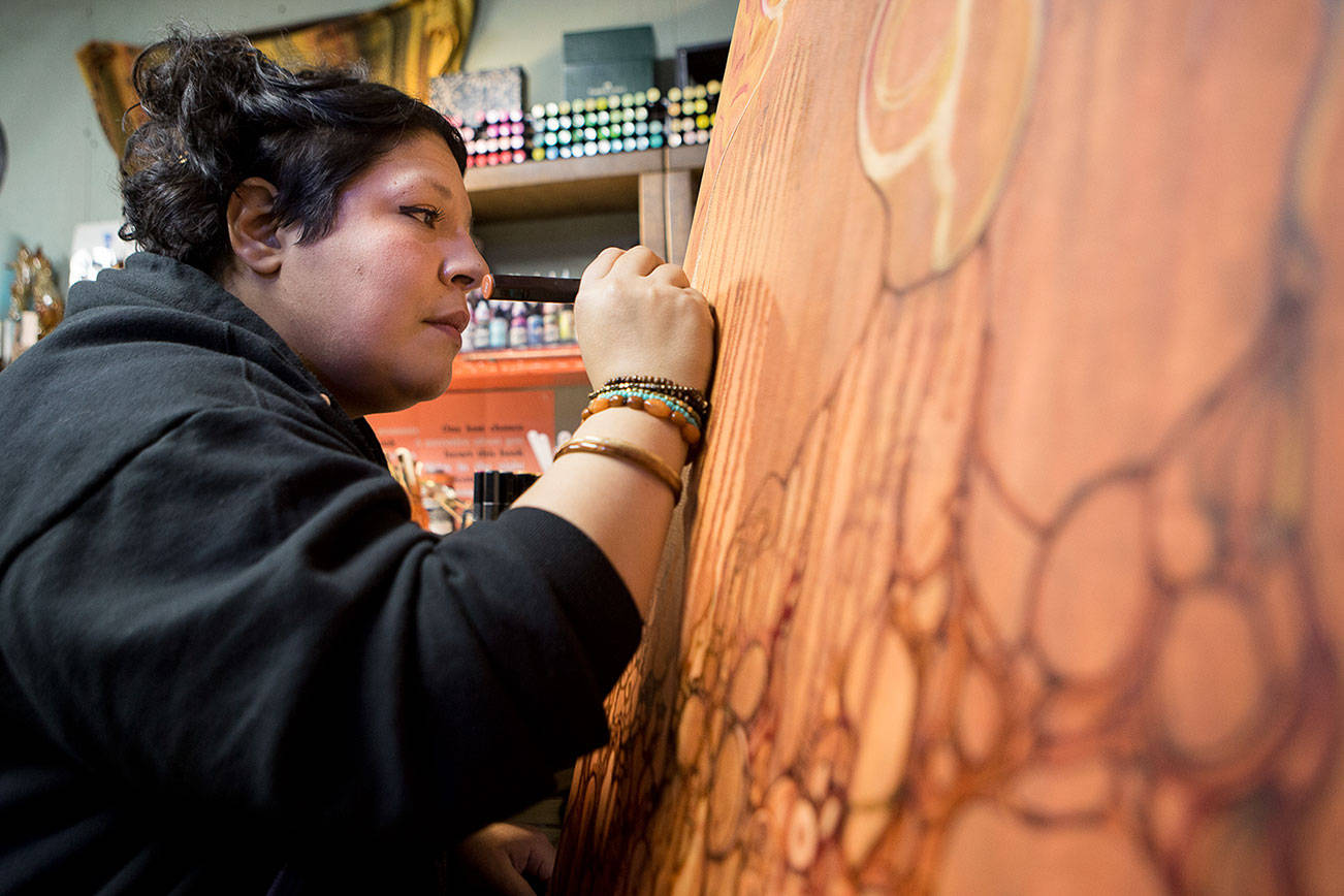Lu Hernandez works on a large canvas piece, Madre Mia, in her studio on Friday, Dec. 11, 2020 in Everett, Wa. (Olivia Vanni / The Herald)