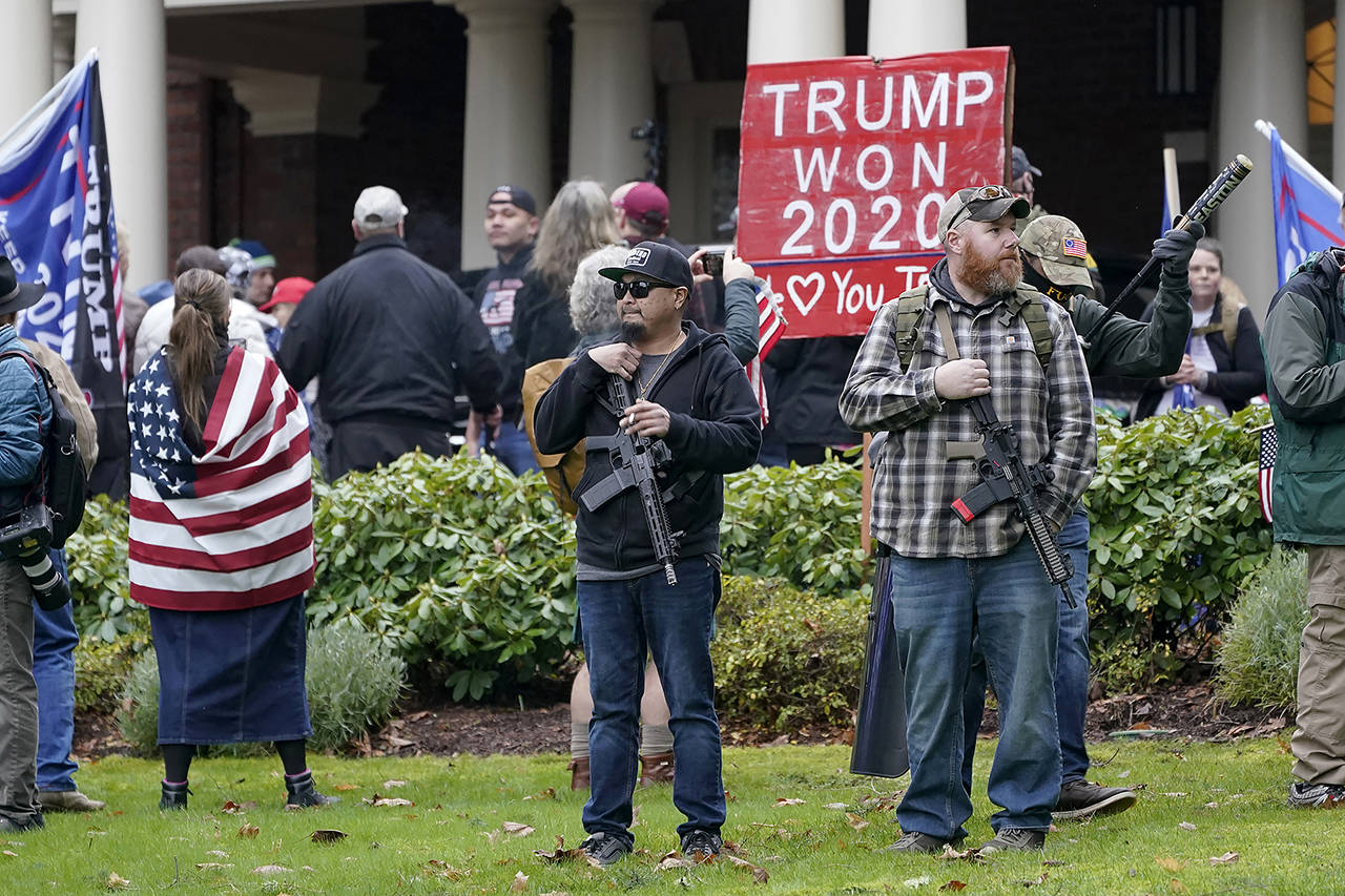 In this Jan. 6 photo at the Capitol in Olympia, two men stand armed with guns in front of the Governor’s Mansion during a protest supporting President Donald Trump and against the counting of electoral votes. (AP Photo/Ted S. Warren, File)