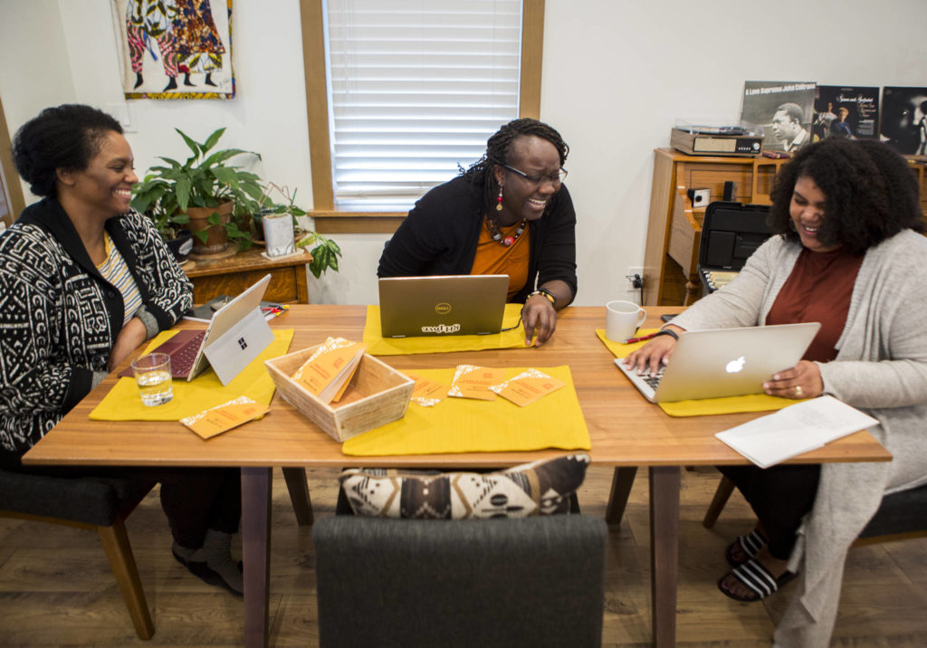 Co-founders of Black Snohomish County Carissa Walker (left), Maïmouna Fame and Avianca Walker-Loundermon laugh while they work on social media posts for the BlackSnoCo accounts on Feb. 23 in Everett. (Olivia Vanni / The Herald)
