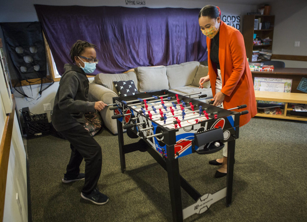 Elwin Pittman, 10, plays foosball with Ashley Kiboigo, who started the Safe Haven WiFi Cafe in Everett. (Olivia Vanni / The Herald)
