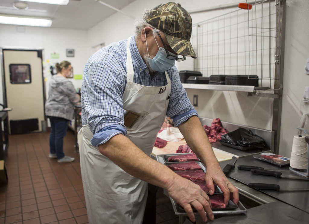 Kevin Ashe (right) and his daughter, Carly Nations, prep meat before opening time at the IGA in Darrington. (Olivia Vanni / The Herald)

