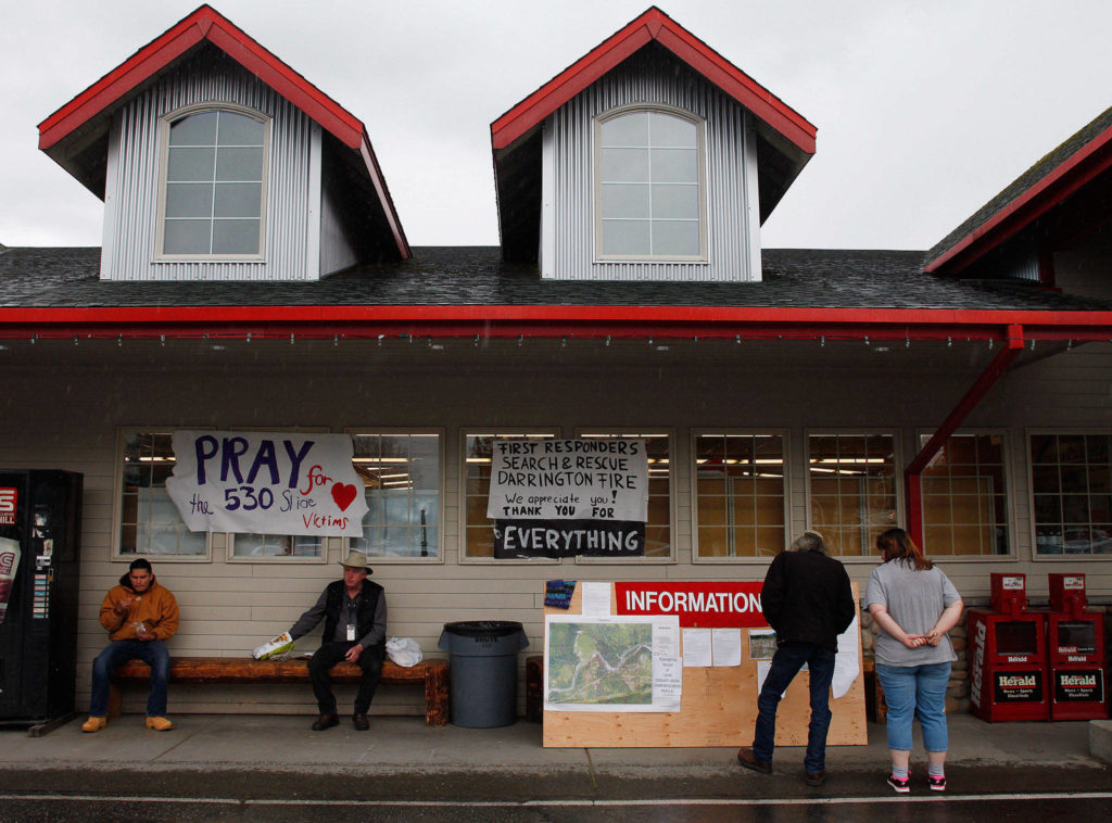 People gather outside the IGA grocery store to read the latest information on the Oso mudslide on Tuesday, March 25, 2014 in Darrington, Wash. (Genna Martin/The Herald)
