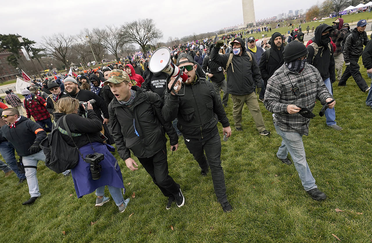 In this Jan. 6 photo, Ethan Nordean, with backward baseball hat and bullhorn, leads members of the far-right group Proud Boys in marching before the riot at the U.S. Capitol. (AP Photo/Carolyn Kaster, File)