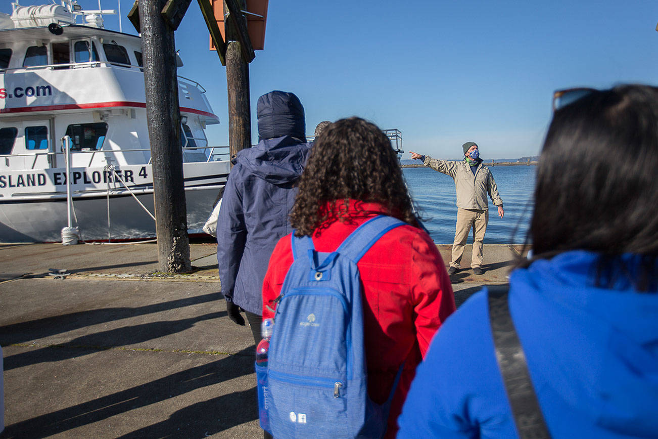 Captain Carl Williams speaks to a socially distanced and masked group of whale watchers before boarding the Island Explorer 4 on Thursday, March 11, 2021 in Everett, Wa. (Olivia Vanni / The Herald)