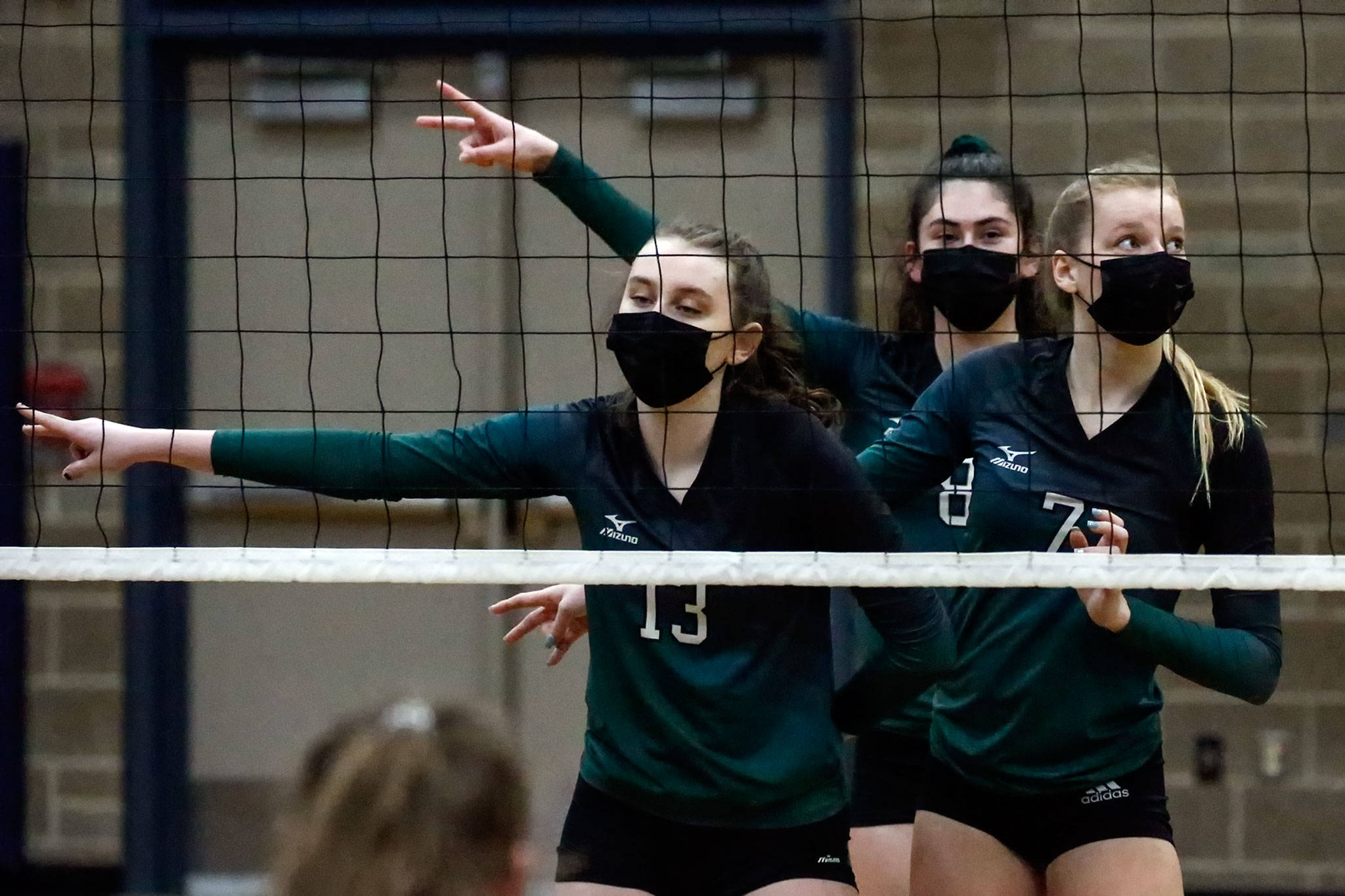 Jackson’s Ainsley Johanson (left-right), Erin Ingram and Ellina Powell await the serve during a match against Arlington on Thursday night at Arlington High School. (Kevin Clark / The Herald)