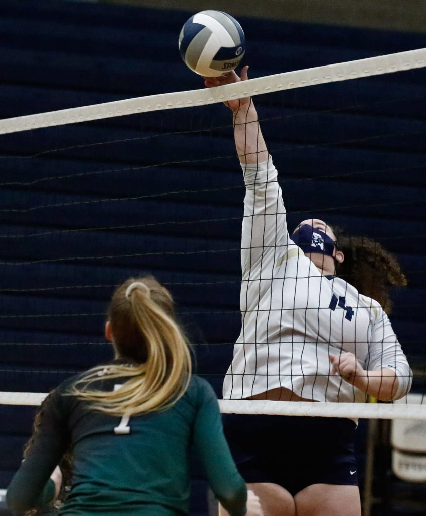 Arlington’s Laura Meno spikes with Jackson’s Ellina Powell (left) Thursday night at Arlington High on March 11, 2021. (Kevin Clark / The Herald)

