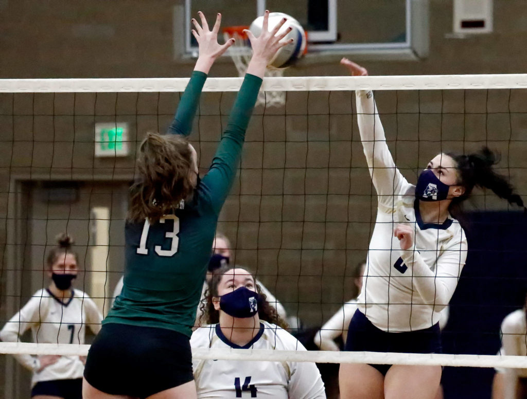 Jackson’s Ainsley Johanson attempts a block on Arlington’s Cassie Whitaker Thursday night at Arlington High on March 11, 2021. (Kevin Clark / The Herald)

