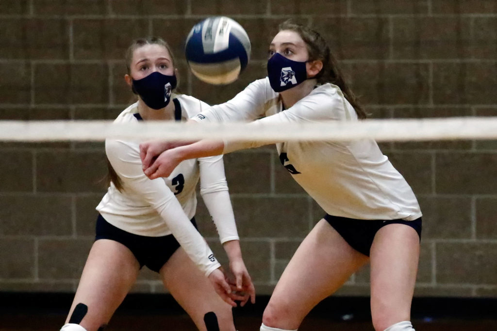 Arlington’s Paige Richards (left) and Brookelynn Ramey look to dig Thursday night at Arlington High on March 11, 2021. (Kevin Clark / The Herald)
