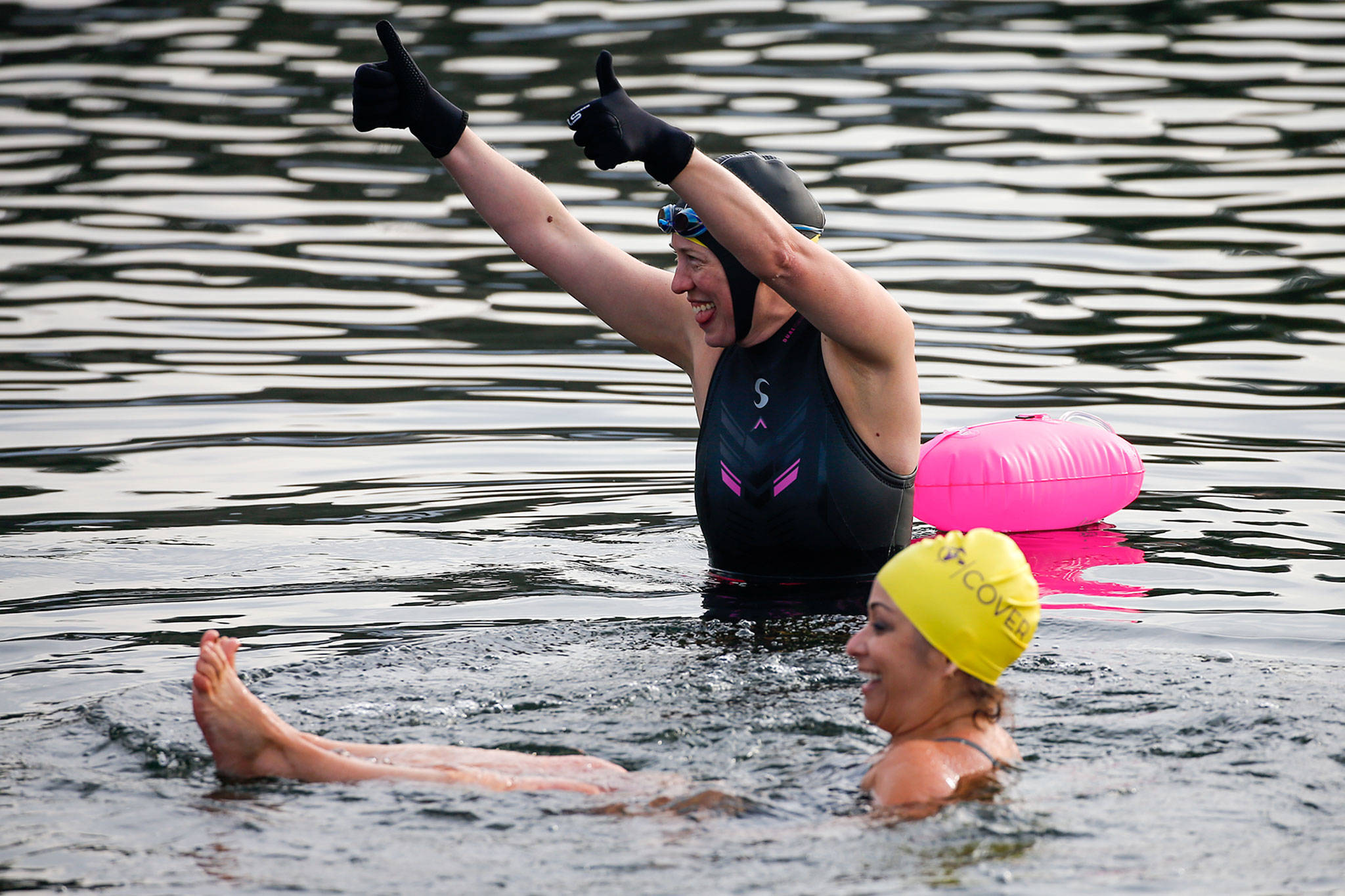 Betsy Schildt (top) and Erin Kendall test the frigid waters of Lake Stevens at Lundeen Park. The Lake Stevens Open Water Swimmers are co-hosting a fundraiser for the YMCA on March 20. (Kevin Clark / The Herald)