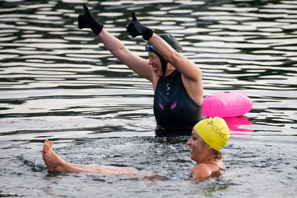 Betsy Schildt (top) and Erin Kendall test the frigid waters of Lake Stevens at Lundeen Park. The Lake Stevens Open Water Swimmers are co-hosting a fundraiser for the YMCA on March 20. (Kevin Clark / The Herald)
