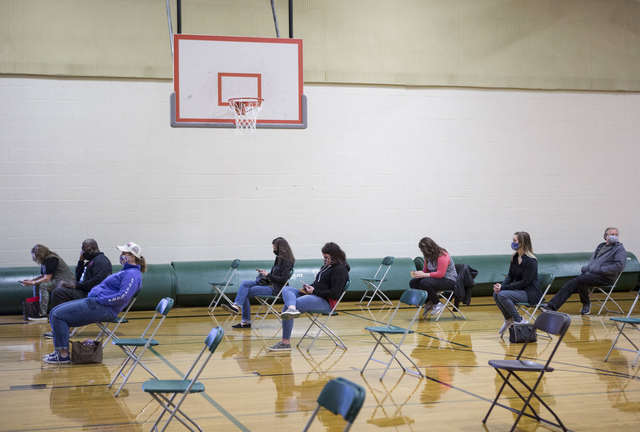 Everett School District teachers and staff wait in the Evergreen Middle School gym for 15 minutes after being vaccinated March 6. (Olivia Vanni / Herald, file)