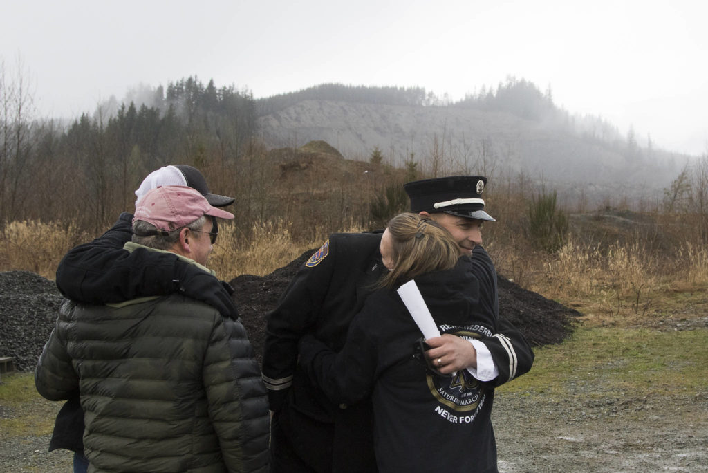Oso Fire Department Capt. Tim Harper hugs Peggy Ray as family and friends gather on the seventh anniversary of the Oso landslide. (Andy Bronson / The Herald) 
