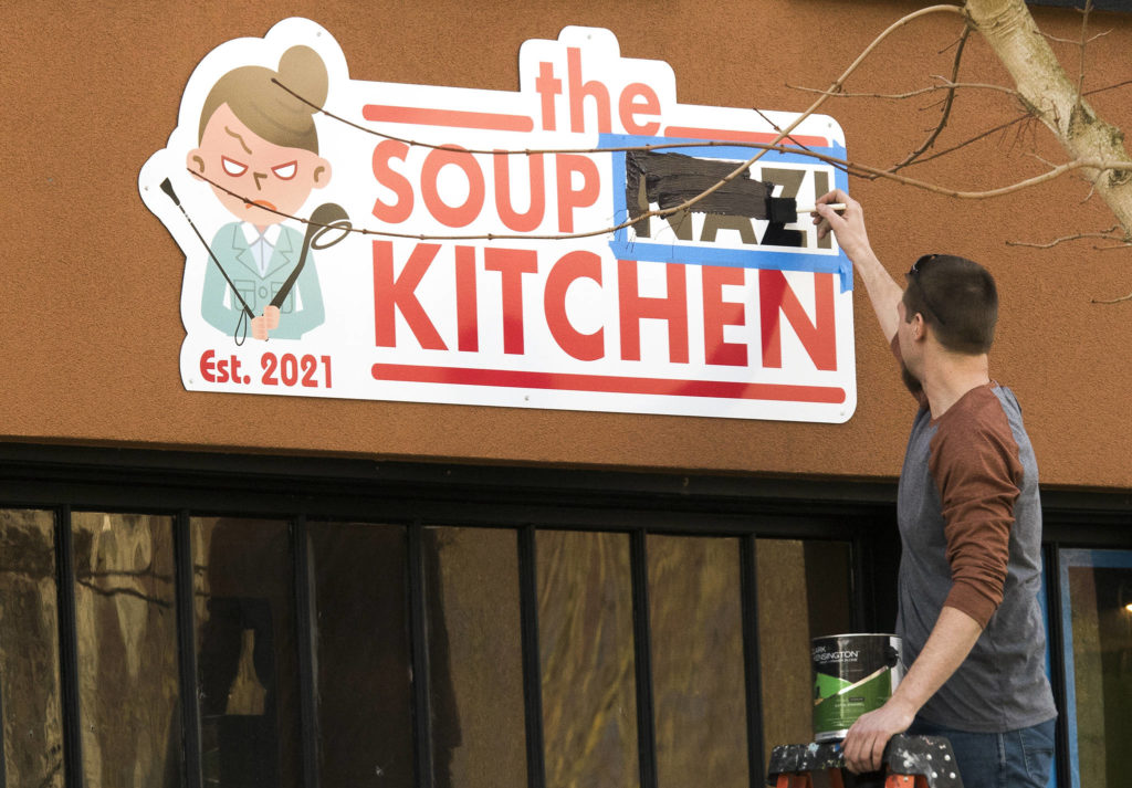 A man paints over the word “Nazi” at the Soup Nazi Kitchen on Hoyt Avenue on Wednesday in Everett. (Andy Bronson / The Herald)
