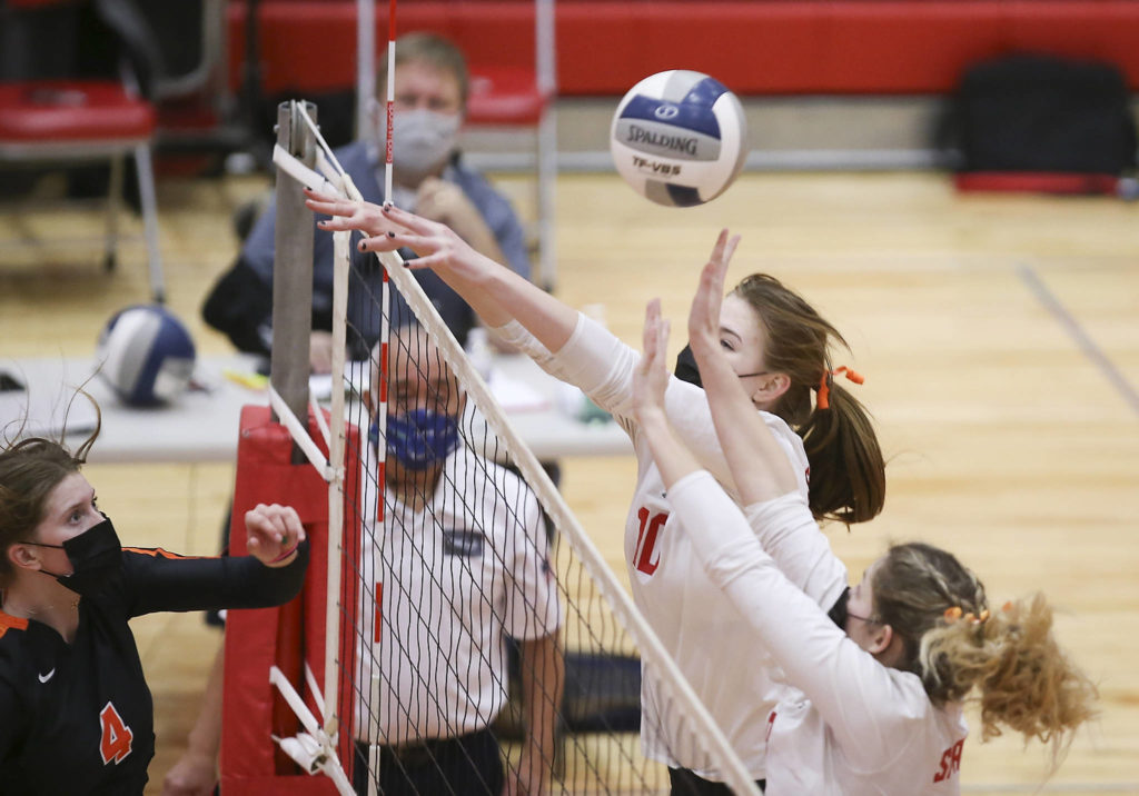 Monroe’s River Mahler spikes the ball past two Stanwood defenders as Stanwood took on Monroe in a volleyball game on Wednesday, March 17, 2021 in Stanwood, Washington. (Andy Bronson / The Herald)
