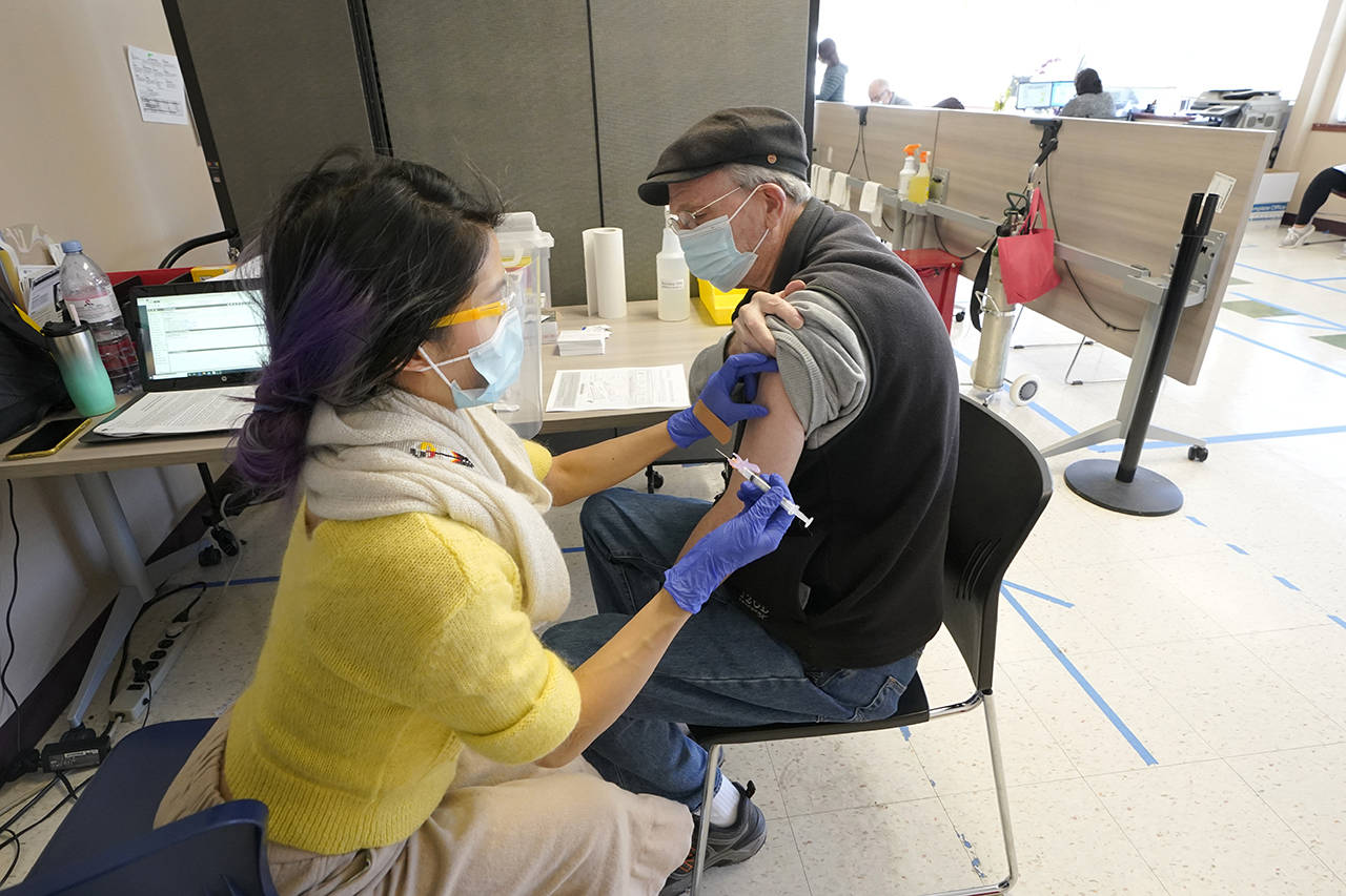 Substitute teacher Oscar Gardner, 76, gets the first dose of the Moderna COVID-19 vaccine from Kim Vo, a pharmacist working for the Seattle Indian Health Board, on Monday at a clinic in Seattle. (AP Photo/Ted S. Warren, file)