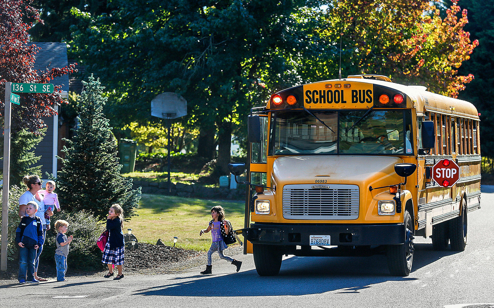 In a Seattle Hill area neighborhood, Penny Creek Elementary students arrive safely home on a Wedensday afternoon on their school bus in September 2016. More school buses could return to the roads with a gradual reopening of schools ordered this week by Gov. Jay Inslee. (Dan Bates / Herald file photo)