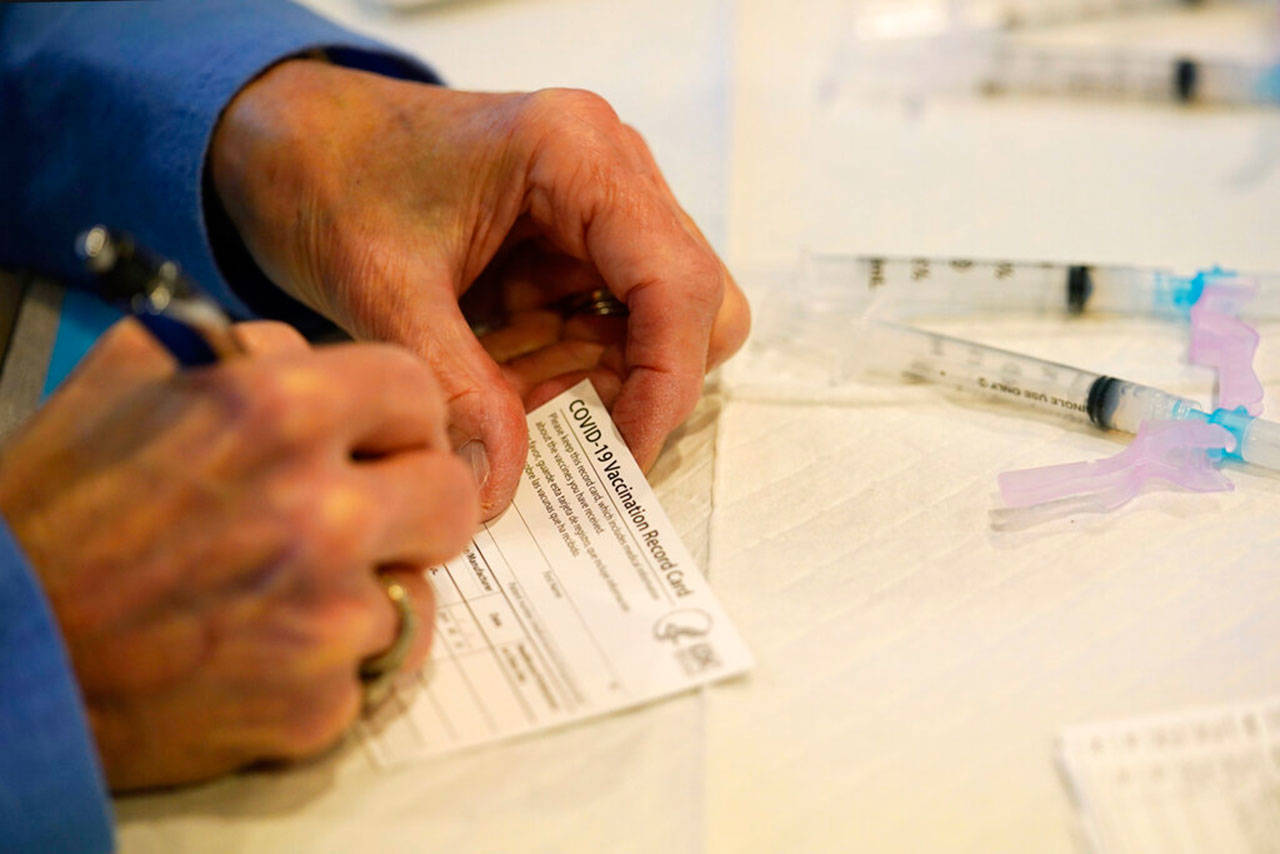A county health department worker fills out a vaccination record card before administering the Moderna COVID-19 vaccine to emergency medical workers and health care personnel at the Chester County Government Services Center in West Chester, Pa., on Dec. 29, 2020. (AP Photo/Matt Slocum)