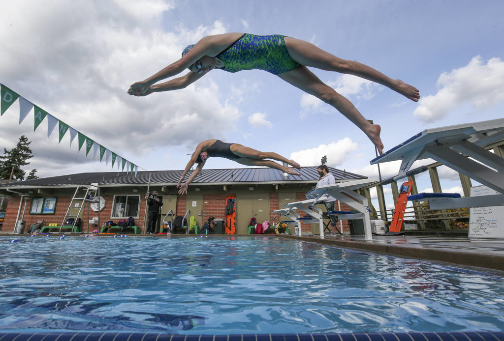 Shorecrest’s Mia Sanchez (top) and Elle Howson take off from the blocks as the girls swim team practices at a four-lane outdoor pool at Sheridan Beach Community Club on Tuesday in Lake Forest Park. The Shoreline Pool closed down when COVID hit and left the Shoreline School District without an indoor facility to practice at. (Andy Bronson / The Herald)
