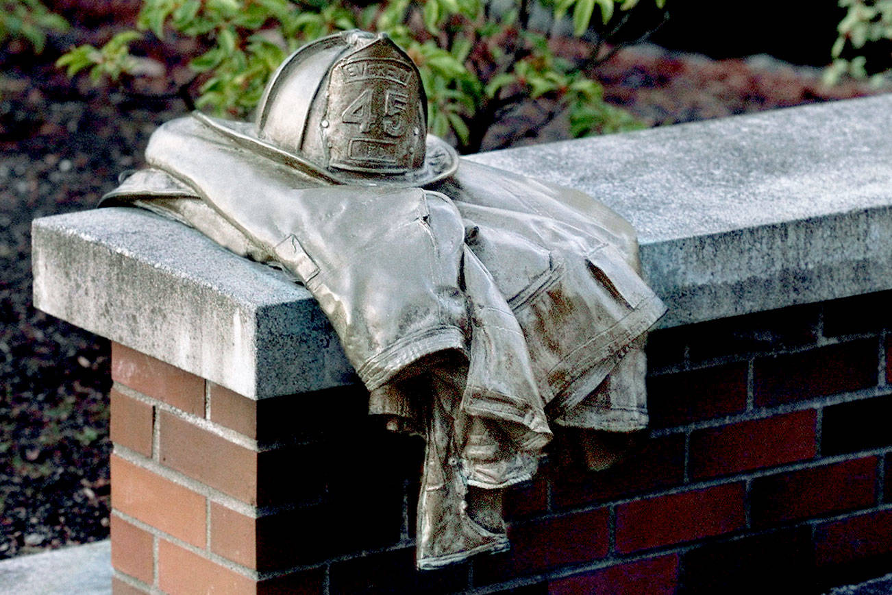Dan Bates / Herald File
A bronze firefighter's helmet and turnout jacket is mounted on a bench at a Gary Parks memorial outside the Everett Community College library.
