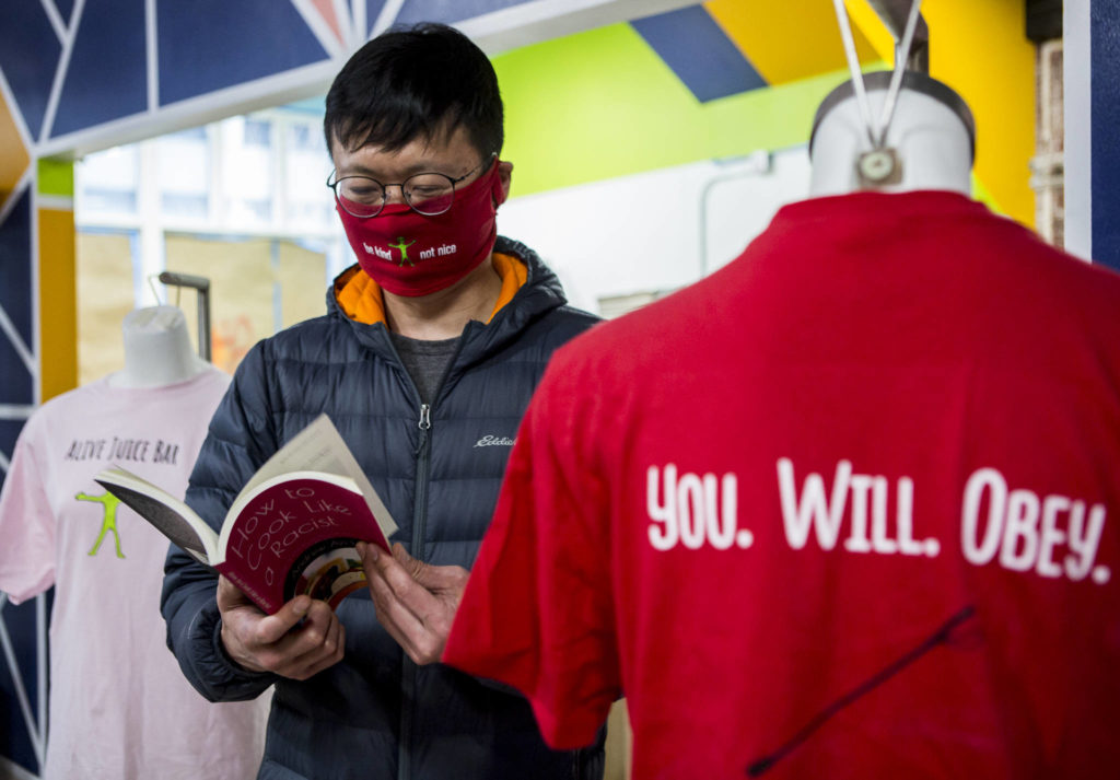 Andrew Ho flips through his book, “How to Cook Like A Racist,” inside his new juice bar and soup kitchen on Wednesday in Everett. (Olivia Vanni / The Herald)
