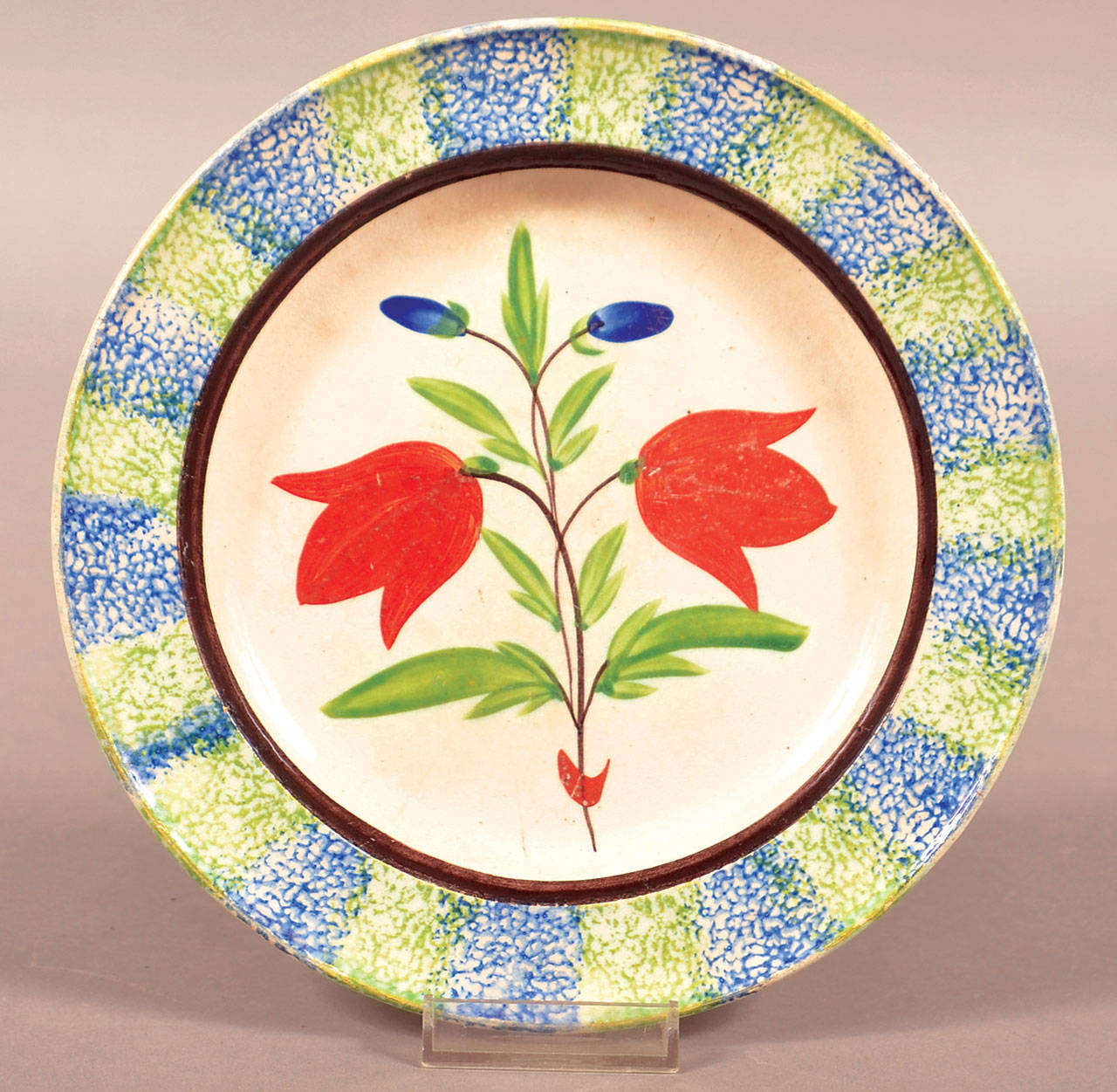 Dinnerware was made with overall spatter or sponged decoration or with a spatter or sponged border and center design. Both are popular vintage collectibles. Price is determined by the condition and the skill of the decorator. Center designs can be a single flower or a scene of rabbits playing baseball. This plate has stylized tulips with a spatter stripe border and sold for $224. (Cowles Syndicate Inc.)