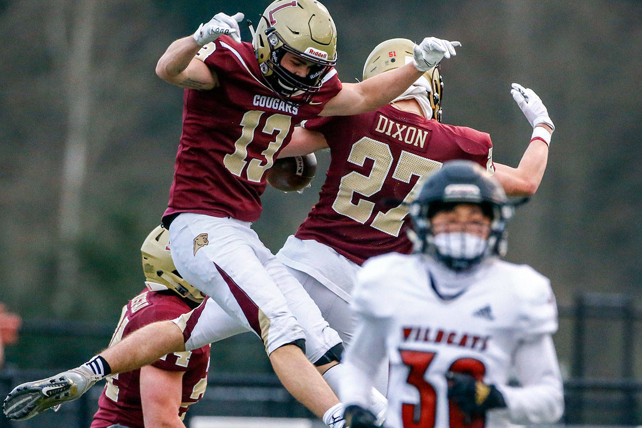 Lakewood's Ethan Guisti and Lakewood's Shae Dixon celebrate a touchdown with Archbishop Murphy's Matthias Bolton at Lakewood High Friday night in Arlington on March 26, 2021. The Cougars won 32-21. (Kevin Clark / The Herald)