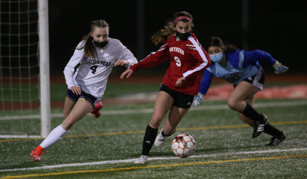 With goalie Kali Cole (rear) scrambling back to her post, Glacier Peak’s Ella Seelhoff tries to beat Snohomish’s Jenna Edelbrock to the ball during a girls soccer match at Veterans Memorial Stadium on Monday in Snohomish. (Andy Bronson / The Herald)
