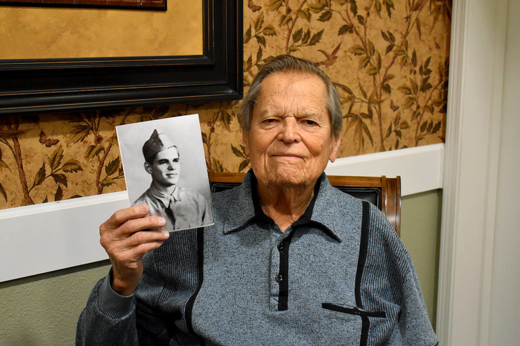 Frank Burns, now in his 90s, holds a photo of himself when he was still in training with the U.S. Army. (Emily Gilbert / Whidbey News-Times)
