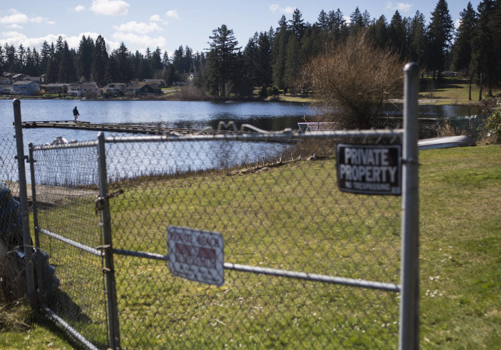 A person fishes off a dock March 10 at Thornton A. Sullivan Park that borders a private beach along Silver Lake and adjacent to West Ibberson Drive in Everett. (Olivia Vanni / The Herald)
