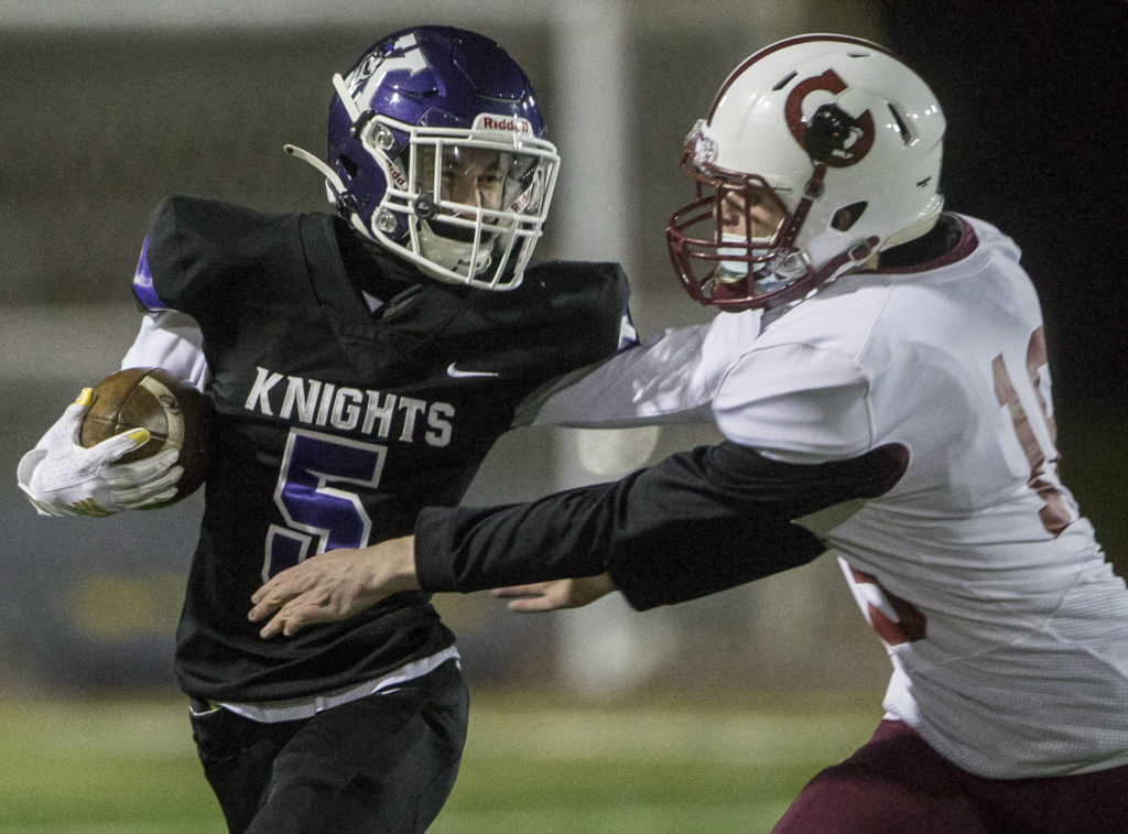 Kamiak’s Dylan James (left) stiff-arms a Cascade defender during a game on April 1, 2021, in Everett. (Olivia Vanni / The Herald)

