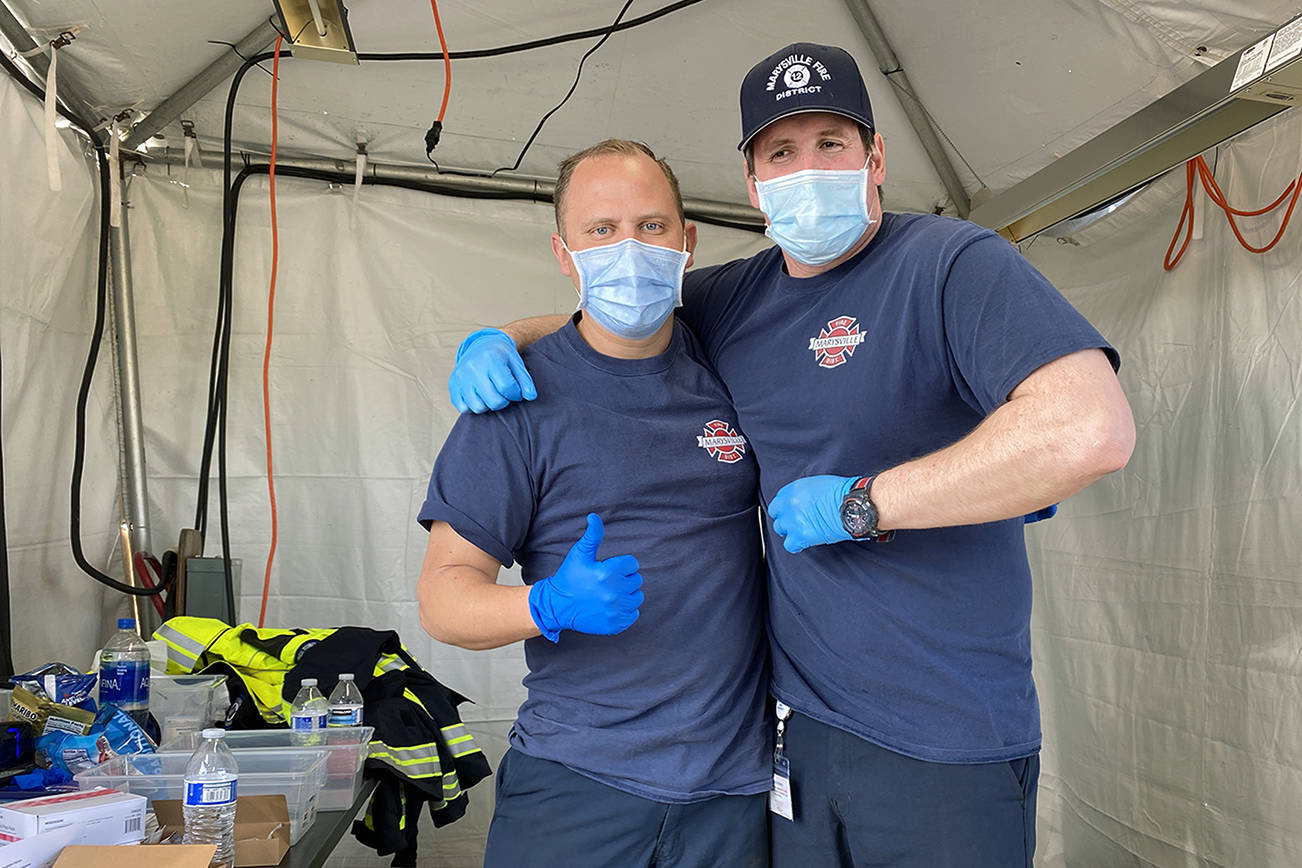 Marysville firefighters Chris Burnette (left) and Chris Lytle (right) were part of the crew vaccinating people at the Arlington Airport on Wednesday. Marysville Fire District is part of the Snohomish County Vaccine Taskforce working to get communities vaccinated. (Sue Misao / The Herald) 210331
