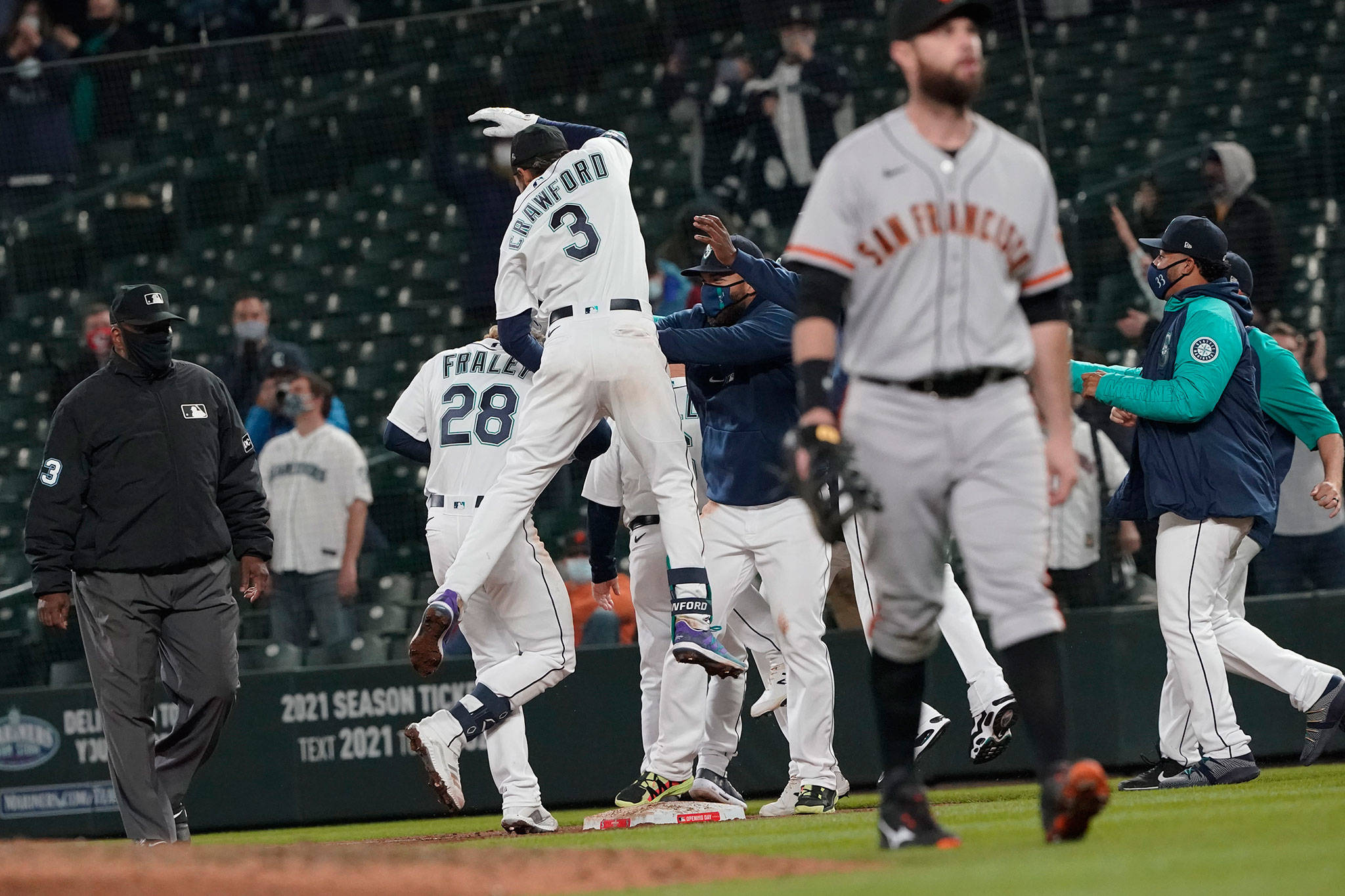 The Mariners’ Jake Fraley (28) is mobbed by teammates, including J.P. Crawford (3), after he was walked with the bases loaded during the tenth inning of a game against the Giants on April 1, 2021, in Seattle. The Mariners won 8-7. (AP Photo/Ted S. Warren)