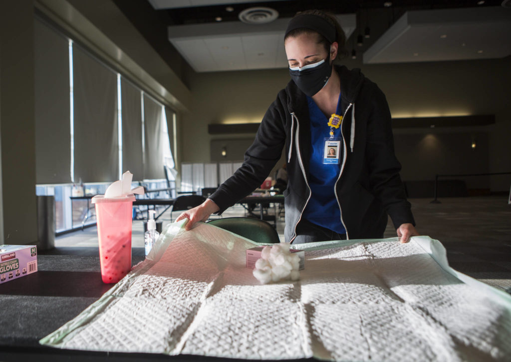 Stenczie Morgan of Maxim Healthcare Services sets up a vaccination station at the Angel of the Winds Area in Everett on Tuesday. (Olivia Vanni / The Herald)
