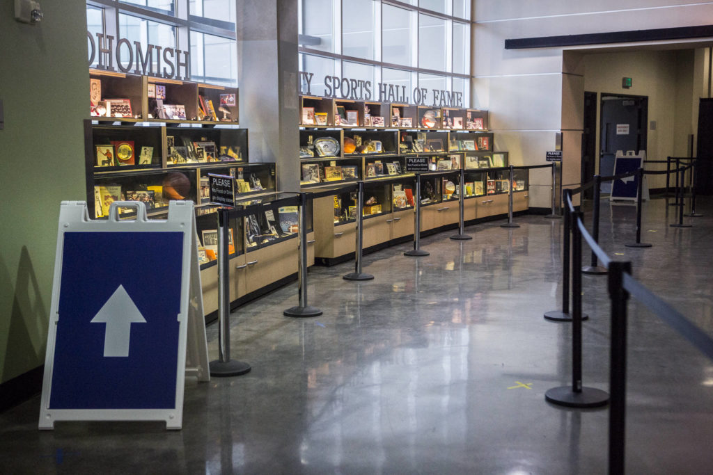 Signs and belt barriers direct people through the vaccination site at Angel of the Winds Arena in Everett. (Olivia Vanni / The Herald) 
