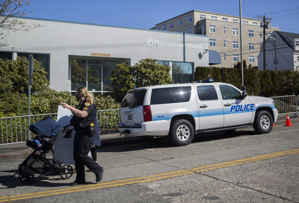Everett Police escort a pro-life supporter down 32nd Street in Everett on Wednesday. Barriers set up along the sidewalk around Planned Parenthood are a part of a “time, place and manner restriction” imposed by the city. (Olivia Vanni / The Herald)
