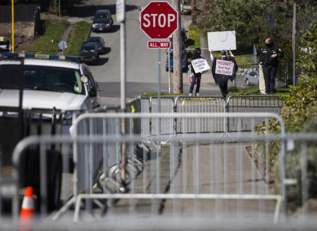Pro-life supporters stand on the corner of Hoyt Avenue and 32nd Street in Everett on Wednesday, across from fencing around Planned Parenthood. (Olivia Vanni / The Herald)
