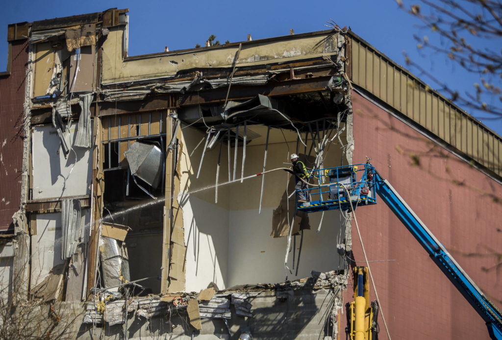 A construction worker sprays water over the demolition site of the former YMCA annex on Tuesday in Everett. (Olivia Vanni / The Herald)
