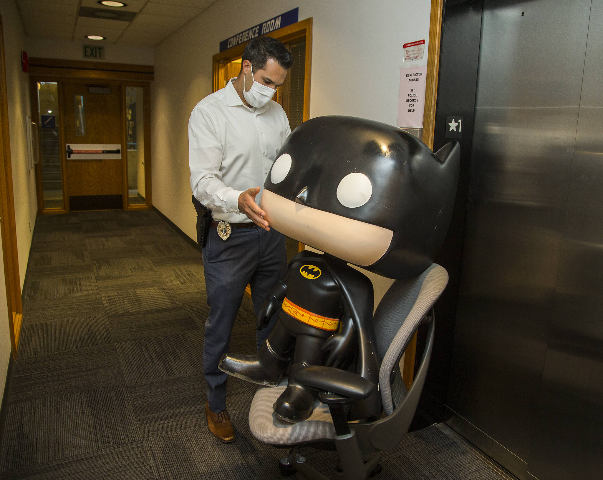 “We are still trying to figure out what to do with him,” said Everett Police Department property crimes Det. Adam Gage, who transports the statue back to a room using a rolling chair. The Batman statue was recovered after it was stolen from an Everett comic book store last year. (Andy Bronson / The Herald)